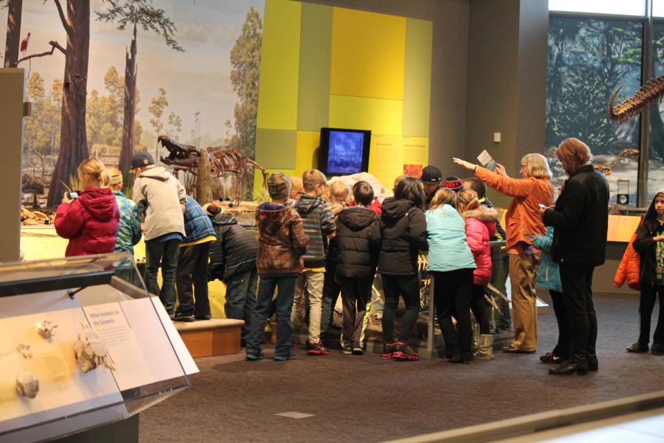 A group of children gather around a museum exhibit