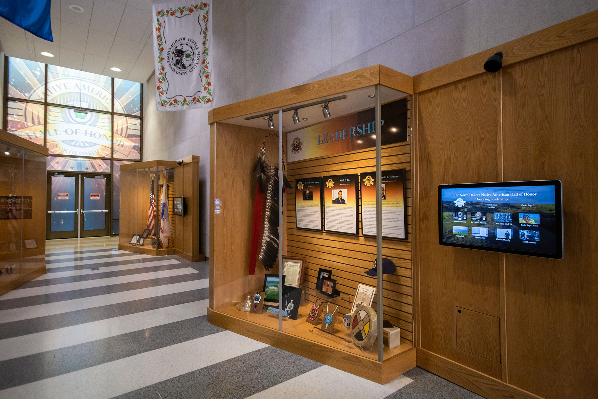 Hallway with exhibit cases with images of Native Americans and artifacts relating to those pictured