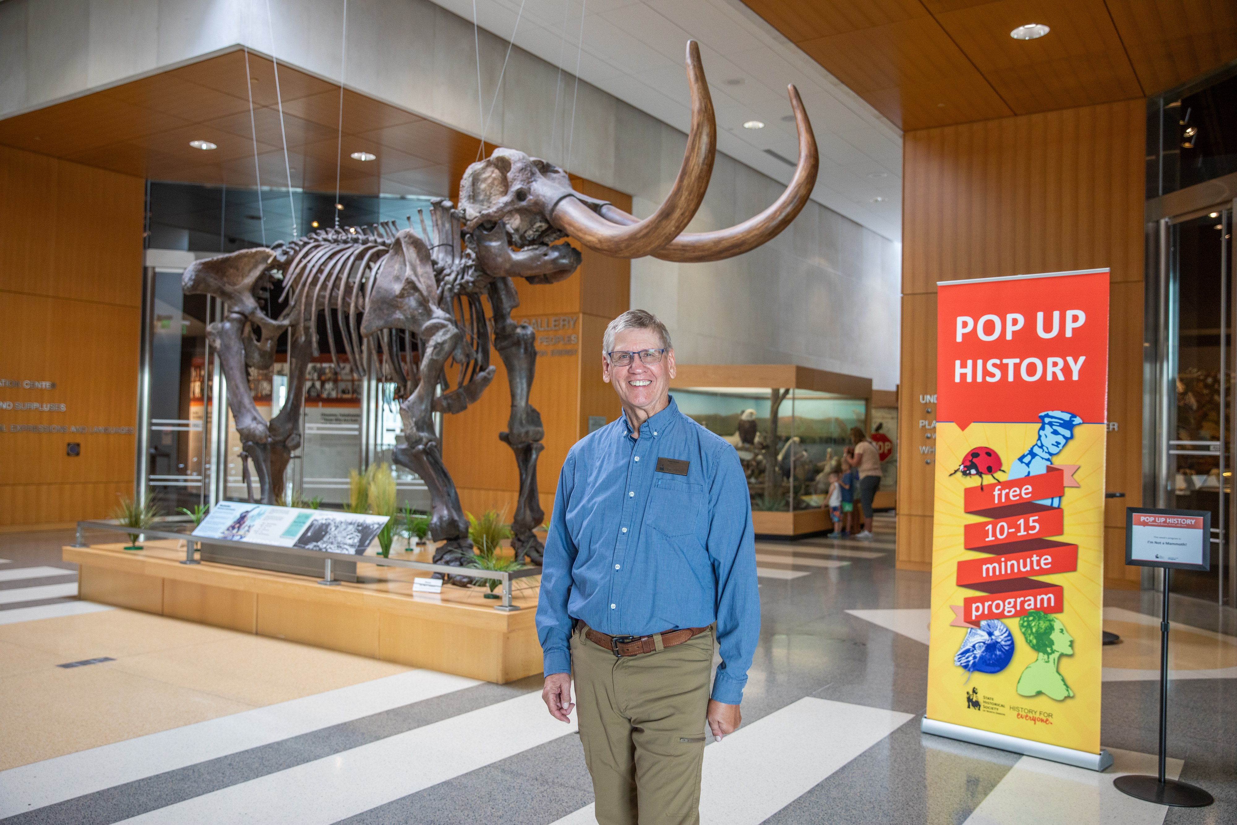 an older gentleman stands next to a pop up banner that reads Pop Up History, free 10-15 minute program
