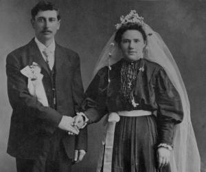 Wedding portrait of a couple wearing wax flowers and ribbons