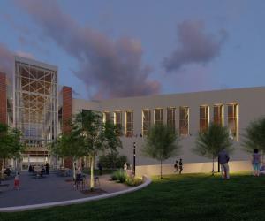A night rendering of the exterior of a building with many windows. People stand in a grassy area and a cemented circular aread outside the doors
