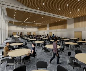 A room with many circular wooden topped tables and black chairs. A few people sit at the tables and walk around.
